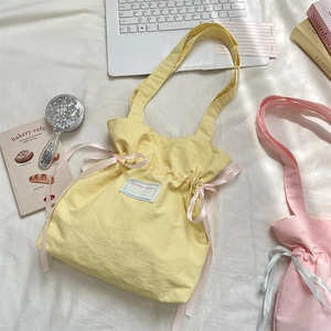Detail of Korean canvas tote bags in yellow and pink with silk ribbon drawstring accents