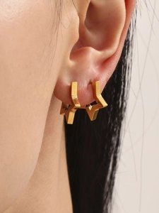 Detail shot of a minimalist 18k gold plated star hoop earring worn by a female model