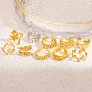 Minimalist gold and silver hollow leaf rings arranged on a beige textured background