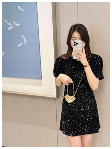 Chic gold lip-shaped chain bag paired with a black sequin dress for a trendy evening look