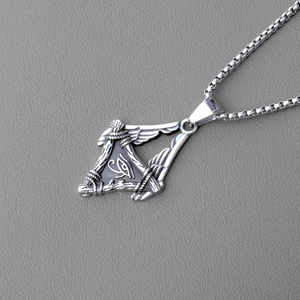 Detail of silver Eye of Horus pendant with wings on a textured grey surface