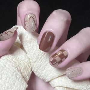 Macro view of short press-on nails with brown checkerboard and speckled patterns