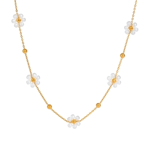 Détail du collier à fleurs tissées avec perles blanches et dorées sur chaîne en or