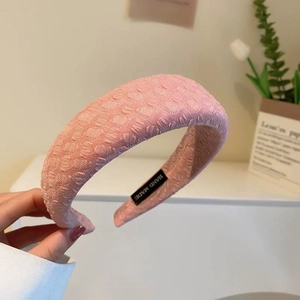 Dettaglio di un cerchietto in tessuto rosa con texture a righe e etichetta fatta a mano