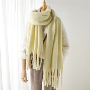 Gros plan d'une écharpe en maille jaune clair avec texture douce et longues franges