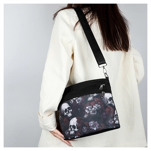Gothic shoulder bag detail with realistic skull and purple floral print on black material