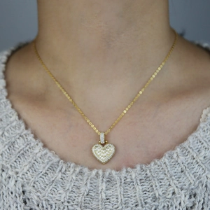 Elegant gold heart pendant necklace with shimmering zircon stones worn by a model