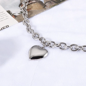 Close-up of a silver heart pendant necklace on a thick chain with smooth metal texture