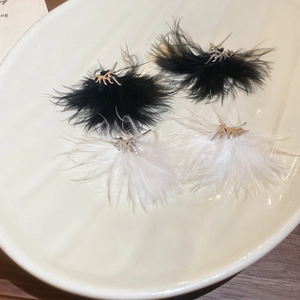Orecchini a nappa con piume bianche e nere e metallo argentato su vassoio in ceramica