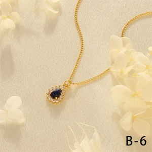 Close-up of heart-shaped gold necklace with blue gemstone and white zircon stones