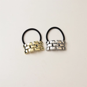 Detail of gold and silver minimalist metallic blocks on high-elasticity black hair ties