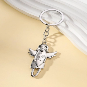 Silver metal angel keychain with heart detail and wings on a minimalist background