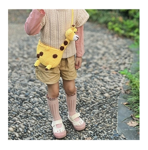 Cute handcrafted yellow giraffe crochet crossbody bag for kids shown in outdoor setting