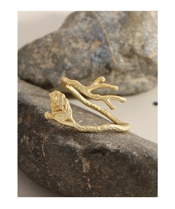 Macro detail of a golden leaf branch ring featuring a matte forged texture on natural stones