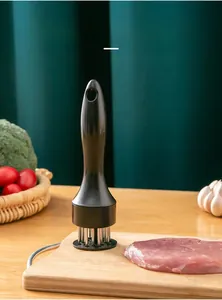 Manual stainless steel meat tenderizer tool with needles on wooden cutting board