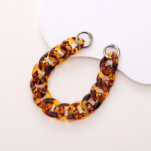 Detail of tortoise shell resin chain accessory with silver metal rings on white background