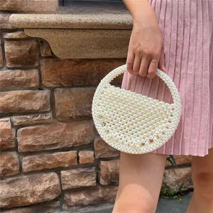 Detail of handmade beaded half-moon handbag featuring pearlescent white beads for weddings