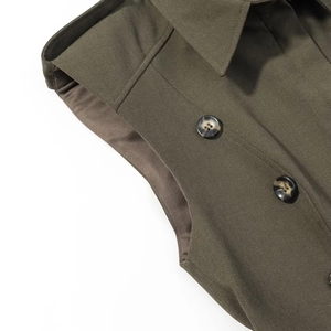 Close-up of olive green double-breasted dress with amber resin buttons and shoulder pads