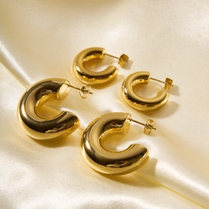 Macro shot of two pairs of gold hoop earrings in different sizes on silk fabric