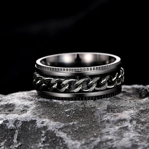 Close-up of rotatable gun grey chain ring with gear texture on dark rock surface