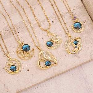 Detailed flat lay of golden necklaces with cosmic pendants on a stone surface