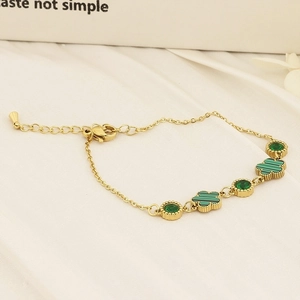 Detail of gold chain bracelet featuring green clover charms and round emerald stones