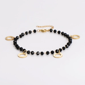 Detail of beaded bracelet with faceted black glass beads and golden round pendant charms
