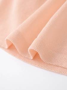 Gros plan sur le tissu en maille rose abricot avec des détails de poignets côtelés