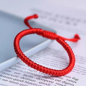 Macro shot of handcrafted red braided rope bracelet on a book with adjustable knot detail