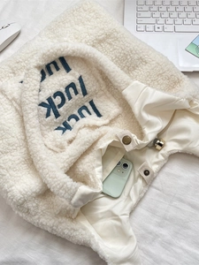 Plush lamb wool tote bag with blue luck embroidery and magnetic closure on white desk