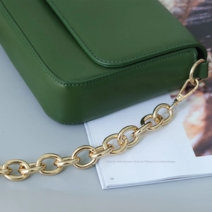 Green leather crossbody bag with chunky gold metal chain strap and lobster clasp detail