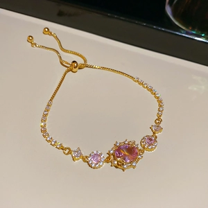 Detailed macro of gold plated bracelet featuring a pink center stone and adjustable slider
