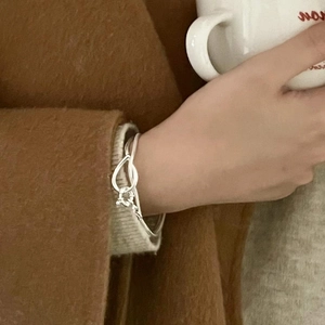 Minimalist S925 sterling silver knot bracelet on woman wrist holding a white ceramic cup