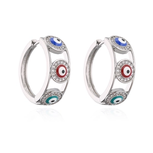 Detailed view of silver hoop earrings featuring blue, red and green evil eye zircon motifs