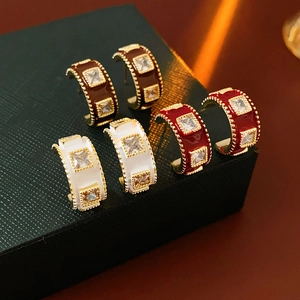 Detail view of gold-plated C-shaped earrings with colorful enamel and zircon stones