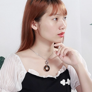 Elegant gold plated stainless steel necklace with round shell pendant shown on model