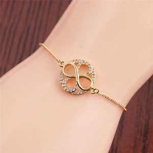 Close-up of golden infinity bracelet with white zircon worn on a model's wrist