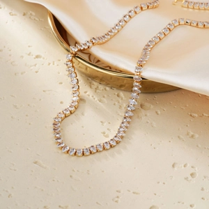 Detail of gold pear-cut zircon necklace on champagne silk with warm lighting
