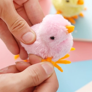 Close-up of hands winding a pink plush clockwork chicken toy with soft fur texture