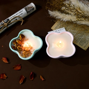 Detail of lit flower shaped scented candles in pink and blue with dried rose petals