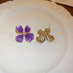 Detail showing the purple flower enamel petals, pearl center, and gold plating on earrings