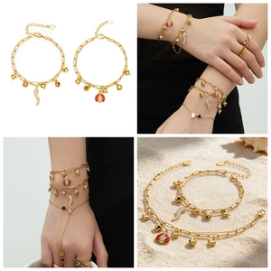 Détail de breloques cœur et coccinelle sur un bracelet double couche en acier doré
