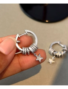 Close-up of silver star earrings with cubic zirconia charms held by hand for detail