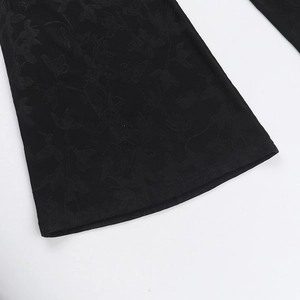Detailed close-up of black floral jacquard fabric with butterfly patterns on trousers