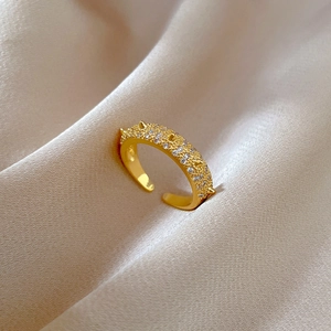 Detailed close-up of a gold-plated open ring with matte texture and sparkling crystals