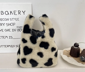 Détail du sac à main en peluche avec motif cœur, texture douce et doublure à carreaux