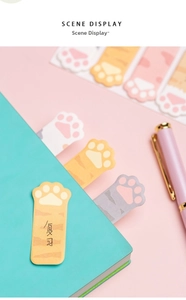 Detailed view of colorful cat paw sticky notes used as bookmarks on a green notebook