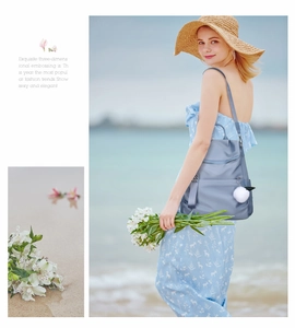 Blue nylon backpack featuring spacious main compartment and decorative white pom-pom charm