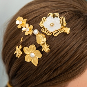 Detailed close-up of gold flower and starfish hair clips set on brown hair texture