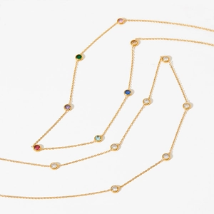 Elegant gold station necklace with colorful round-cut gemstones on a white background